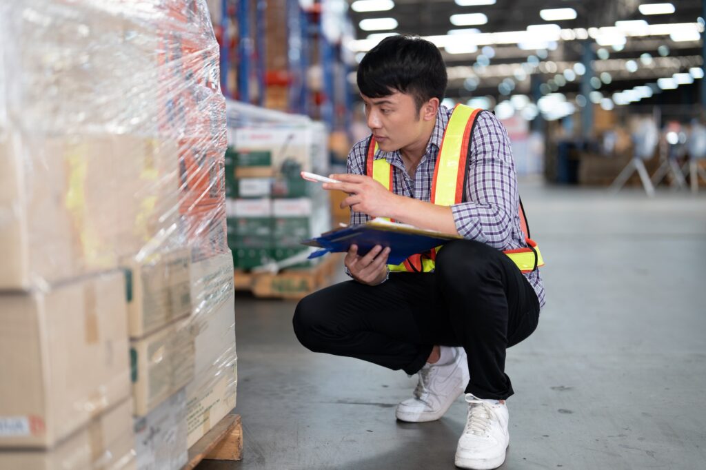 Worker working in large warehouse holding paper chart